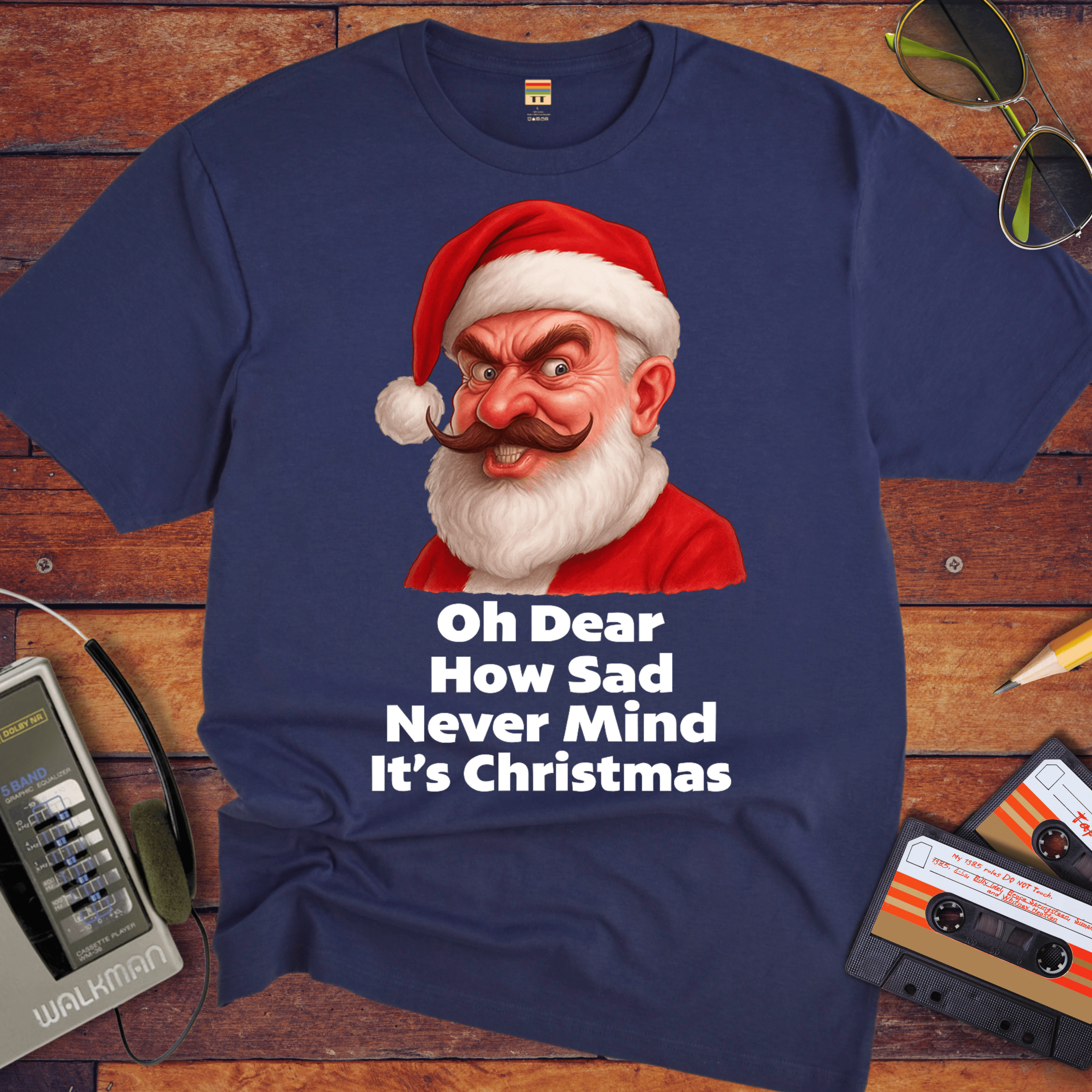 Navy blue t-shirt with a graphic of a character wearing a Santa hat and text on a wooden surface with vintage items.