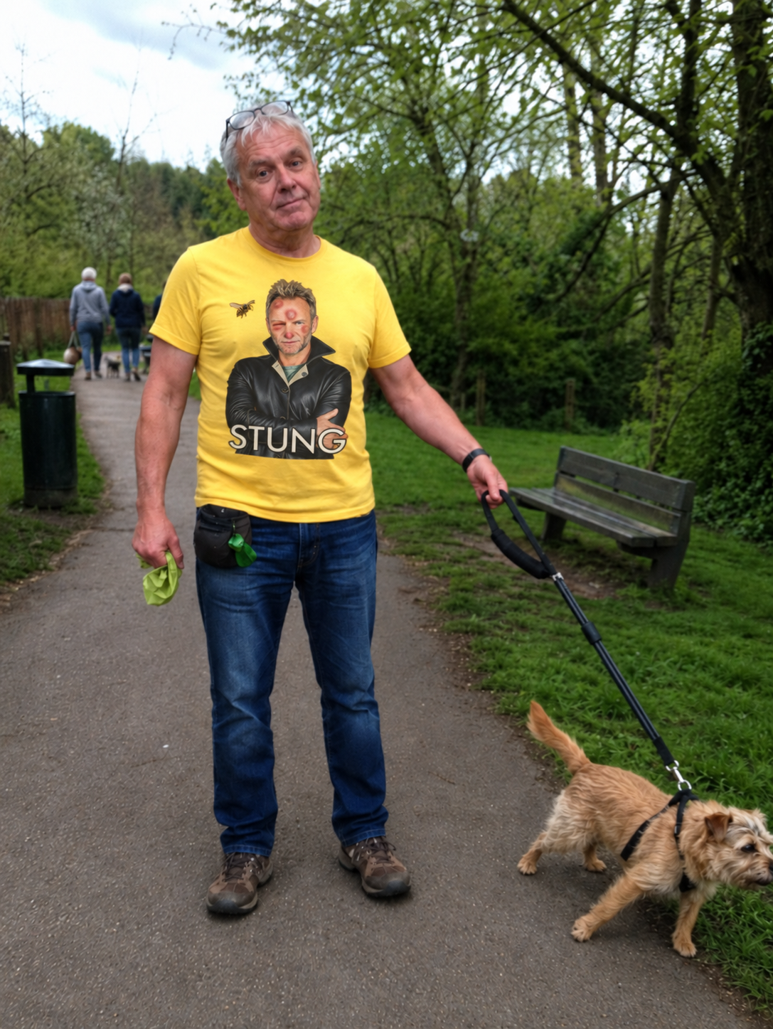 Man walking dog in park wearing yellow Stung graphic T-shirt